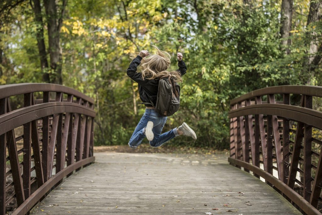 Back to school: a little girl with a schoolbag who jumps for joy 