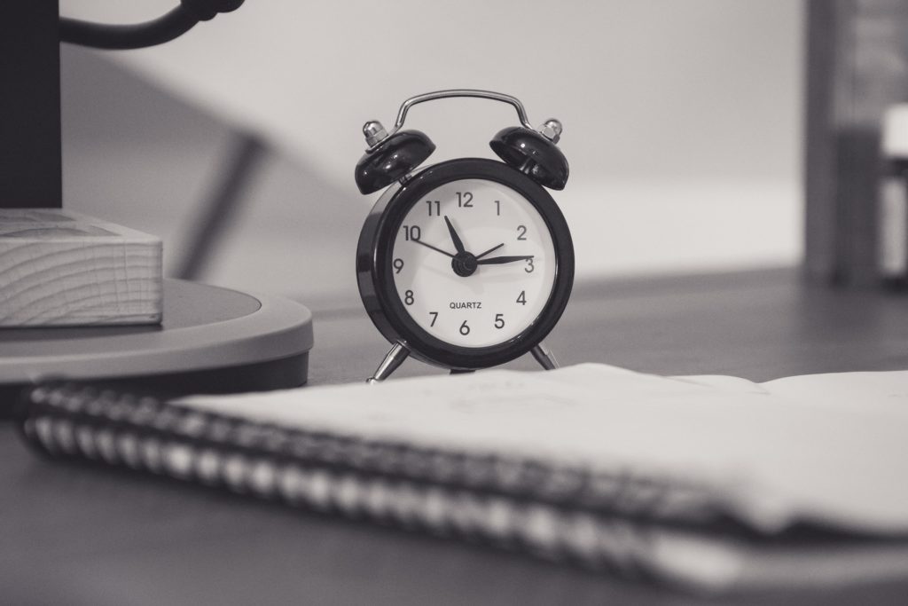 student life and student job: the photo of an alarm clock and a notebook 