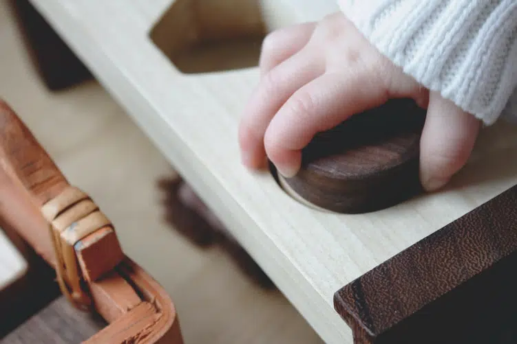 Pédagogie Montessori : main d'un enfant sur un outil Montessori 