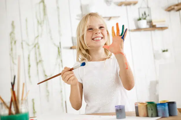 child's drawing: a little girl happy to paint, her hand is all in colors 