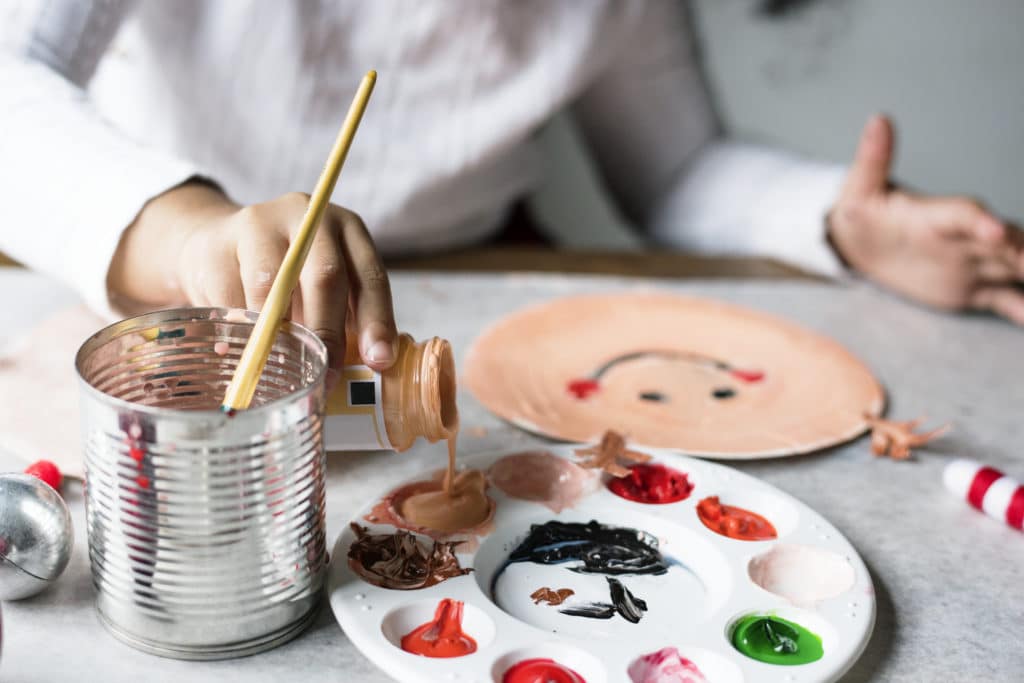 preparing his baby sitting: child painting a paper plate