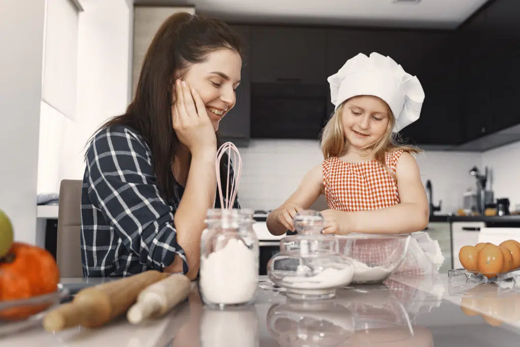 nounou bilingue : 
une babysitter qui fait de la pâtisserie avec une petite fille 