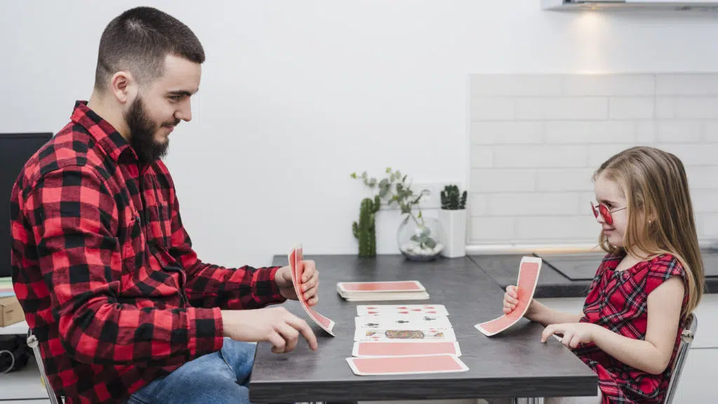 child care at home : nanny and child playing cards