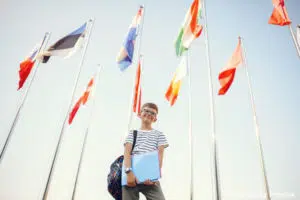 Trouver une nounou bilingue : un enfant debout autour des drapeaux