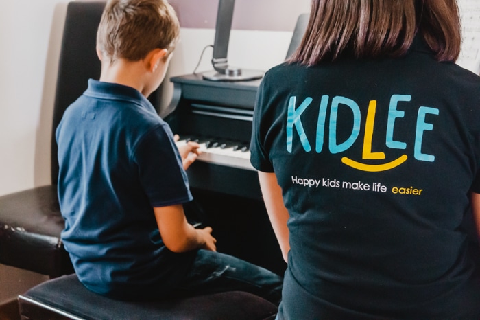 Site de babysitting : 
une babysitter Kidlee en train d'apprendre le piano à un petit garçon 