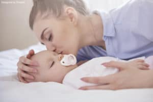 bedtime ritual: a mother kissing her baby