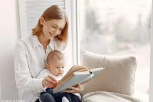 Une baby sitter avec un nourrisson en train de lui raconter une histoire