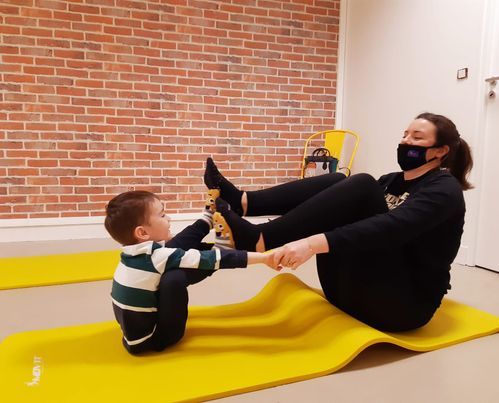 Une coach avec un enfant en train de faire du yoga